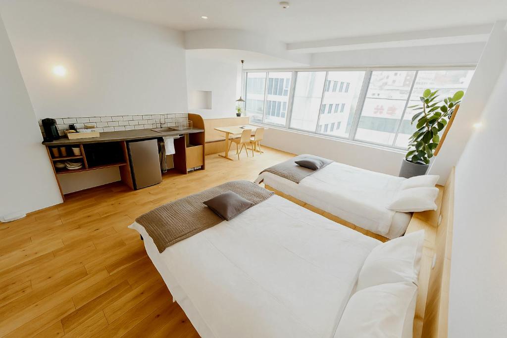 a white room with two beds and a desk at ROI SPACE Kagoshima in Kagoshima