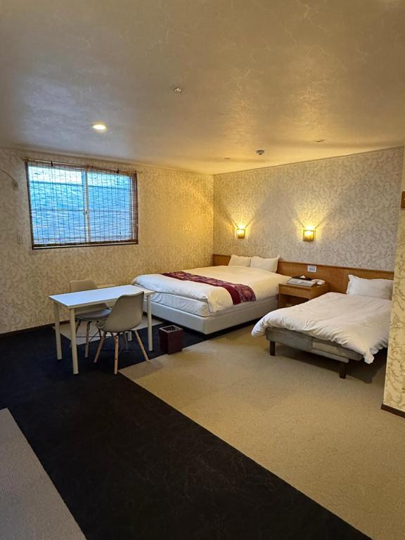 a bedroom with two beds and a desk and a table at Hotel DOLPHIA in Daisen