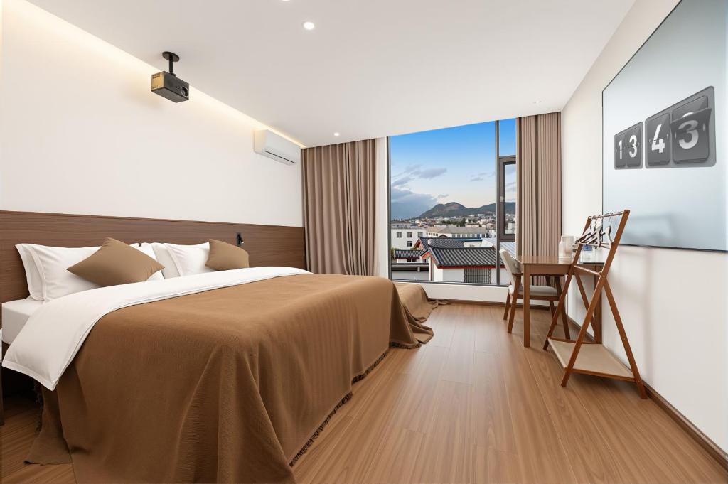 a bedroom with a bed and a desk and a window at 熹楠丽江古城 in Lijiang