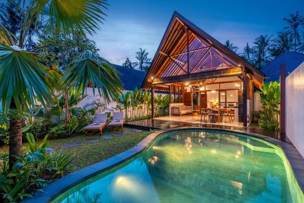 a house with a swimming pool in front of a house at Villa Al-Mulk in Ubud
