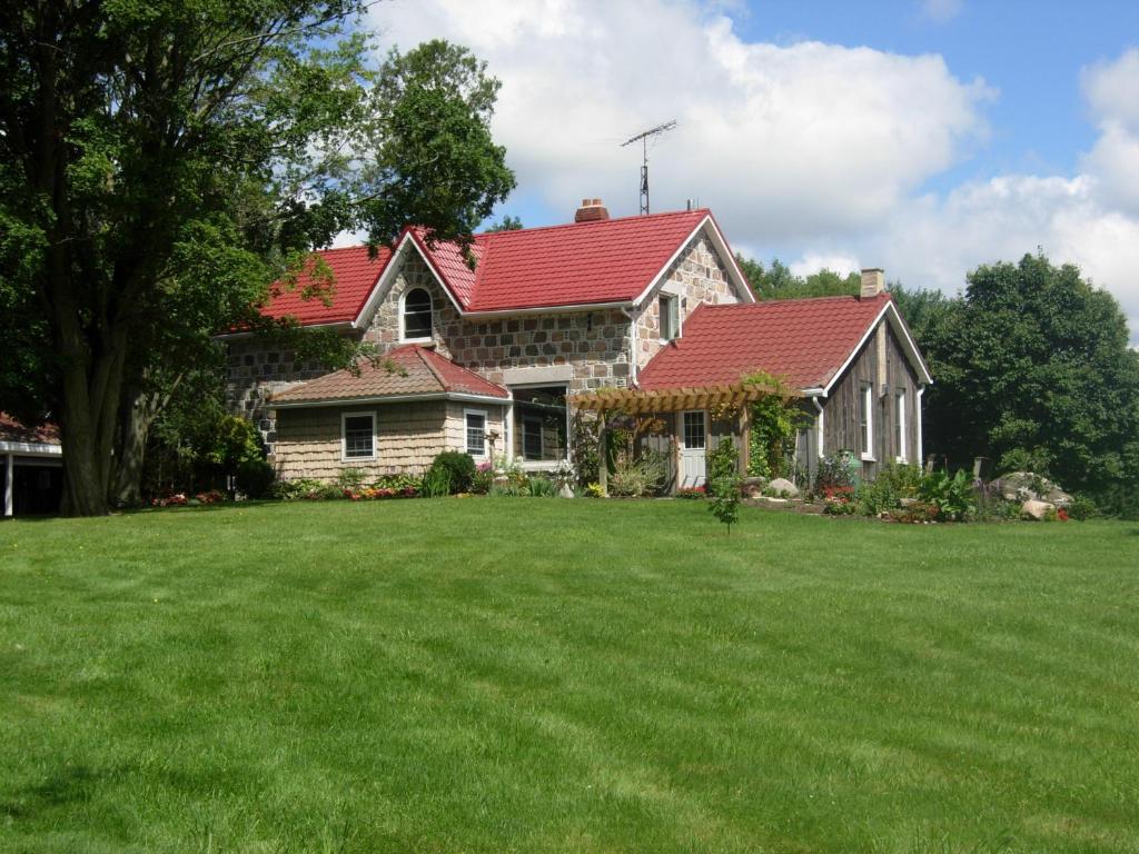 a house with a red roof on a green lawn at Koch Haus Bed and Breakfast in Stratford