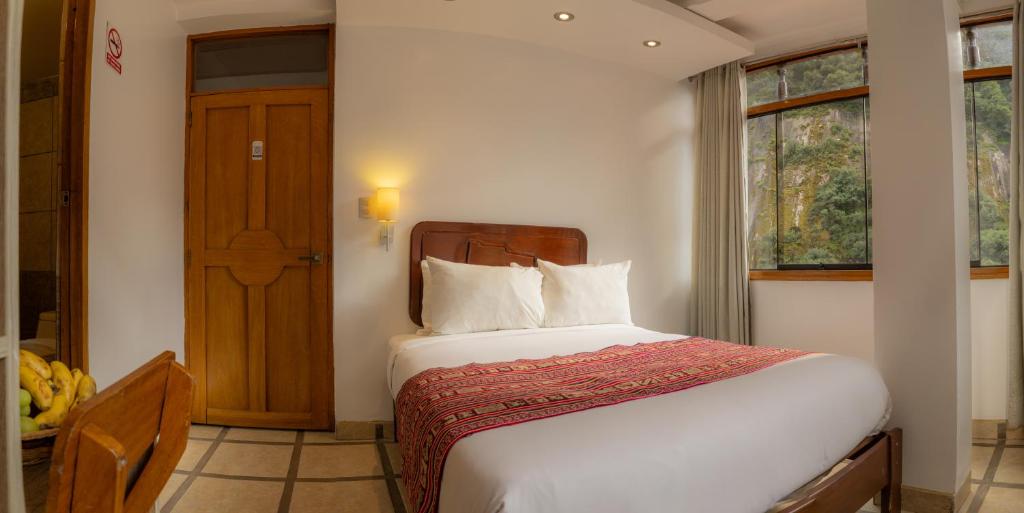 a bedroom with a bed and a window and a door at Seven Machupicchu in Machu Picchu