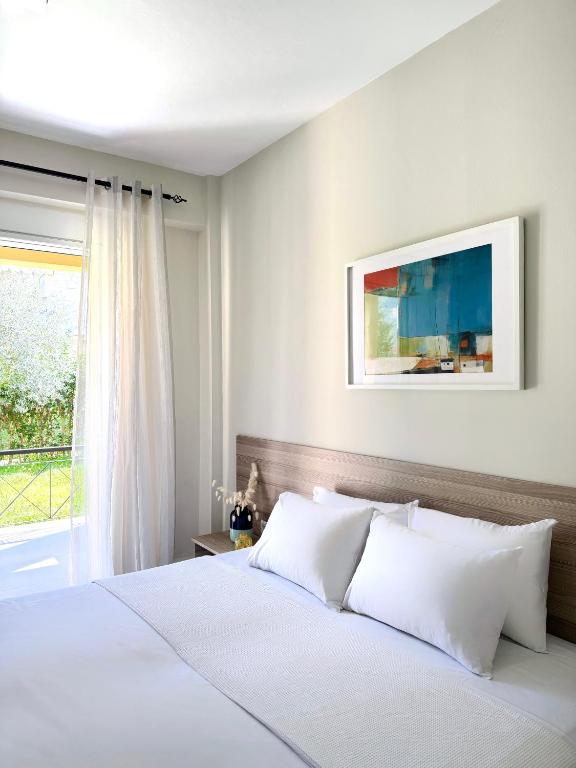 a bedroom with a white bed and a window at Avra Yard Suites in Pefkochori
