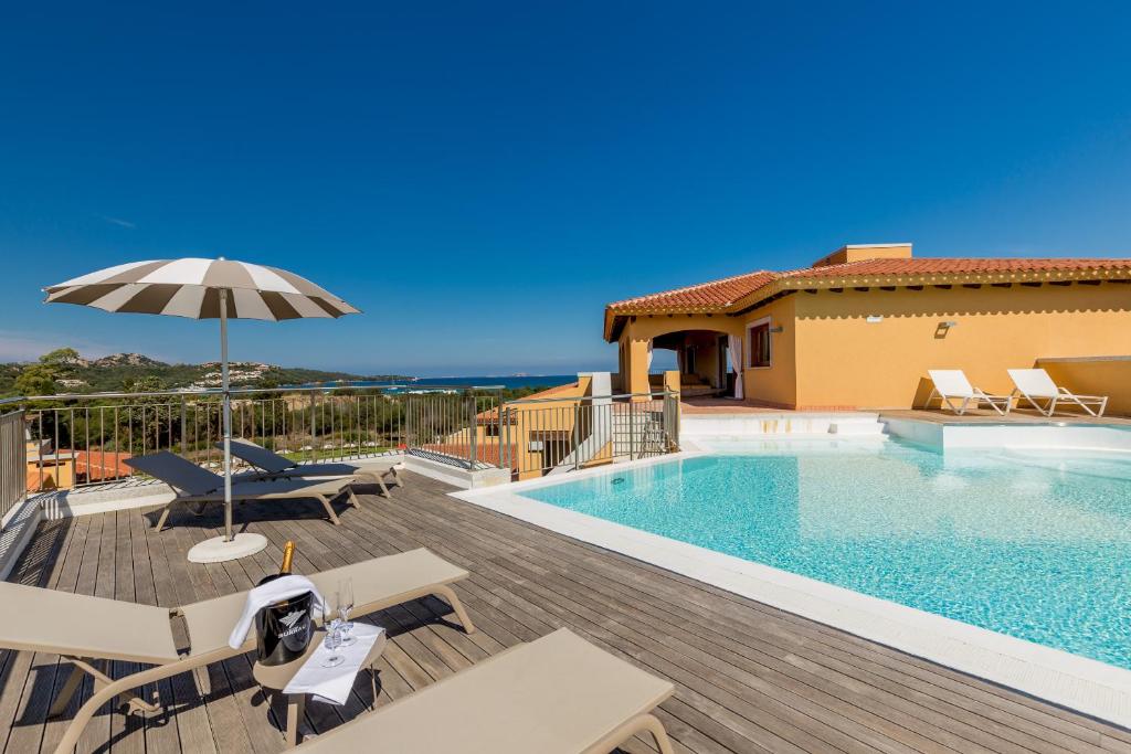 a swimming pool with chairs and an umbrella next to a house at Hotel Marana in Golfo Aranci