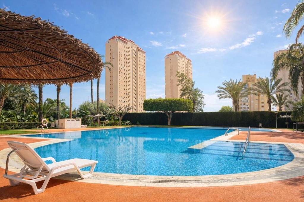 a swimming pool with a chair and two tall buildings at Natura playa By Sunset in La Venteta