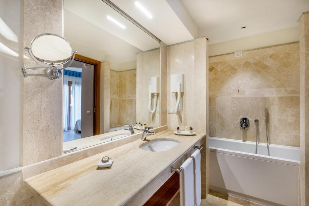 a bathroom with a sink and a tub and a mirror at Hotel Marana in Golfo Aranci