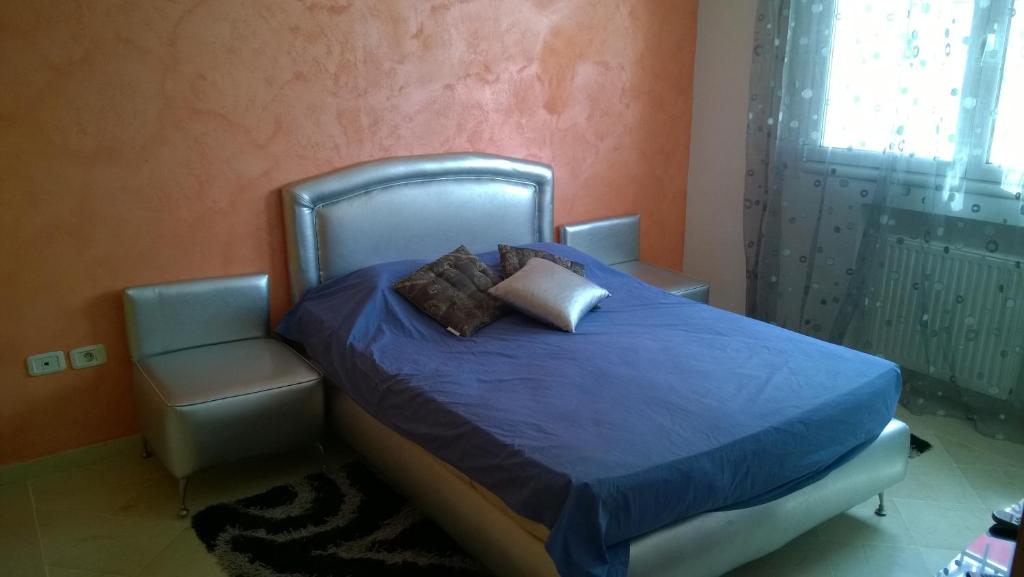 a bedroom with a bed with a blue comforter and a window at Résidence Tasnim in Ariana