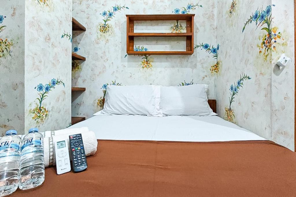 a bed with two remote controls and two bottles of water at Queen Residence Ancol RedPartner in Jakarta