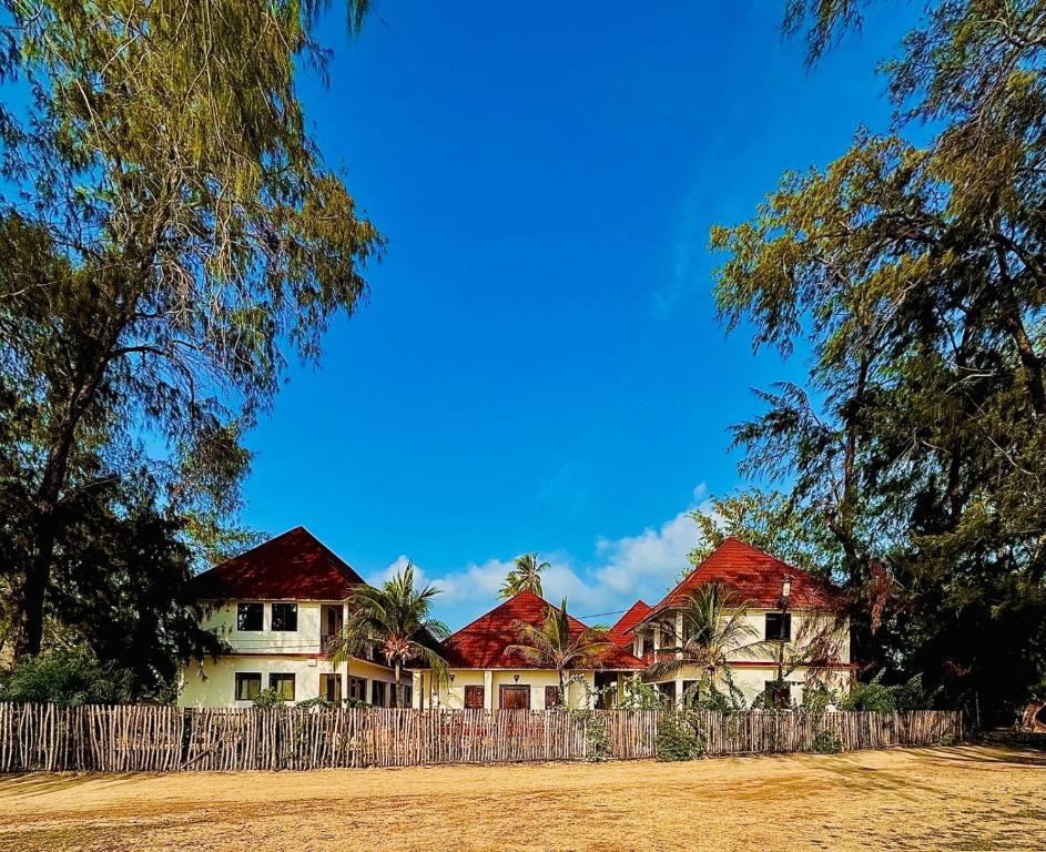 a house with red roofs behind a wooden fence at CAAA Youth Hostel in Kibanguni