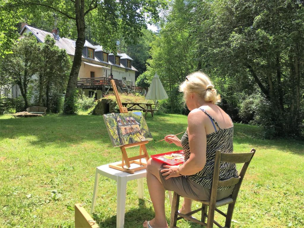 una mujer sentada en una silla frente a una mesa en Moulin de la Fayolle, en Blot-lʼÉglise