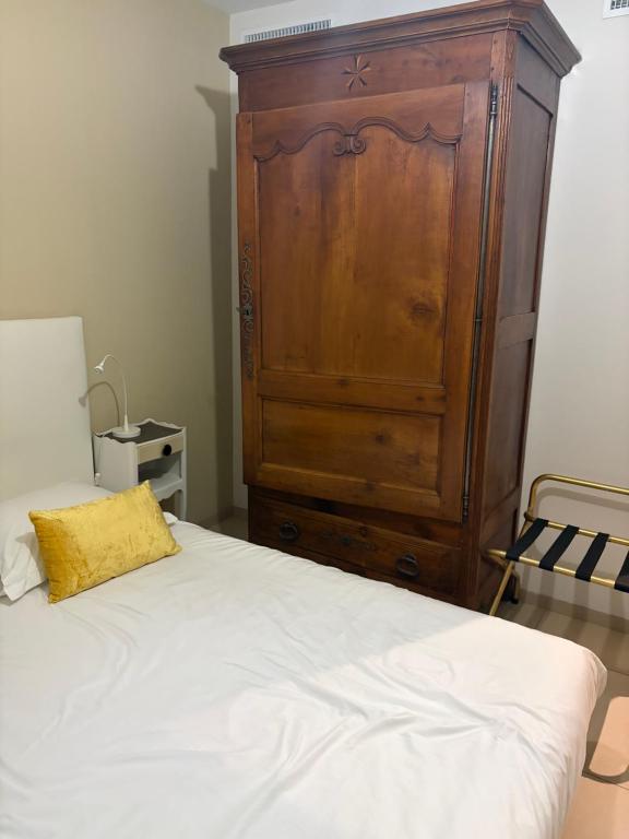 a bedroom with a large wooden cabinet and a bed at La Cosette Janvier in Mios