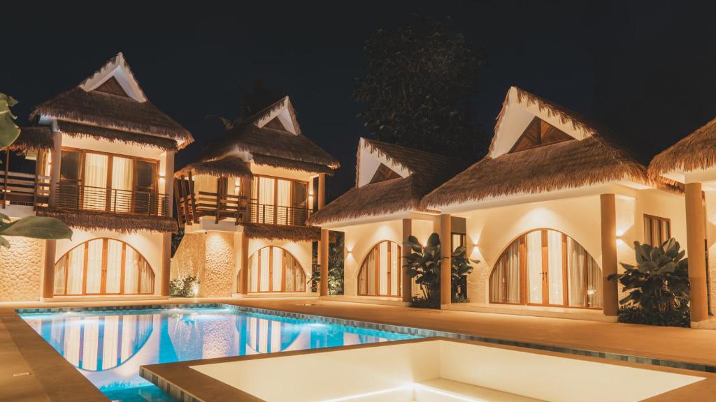 a villa with a swimming pool at night at Sunyata Resort Siargao in Catagnan