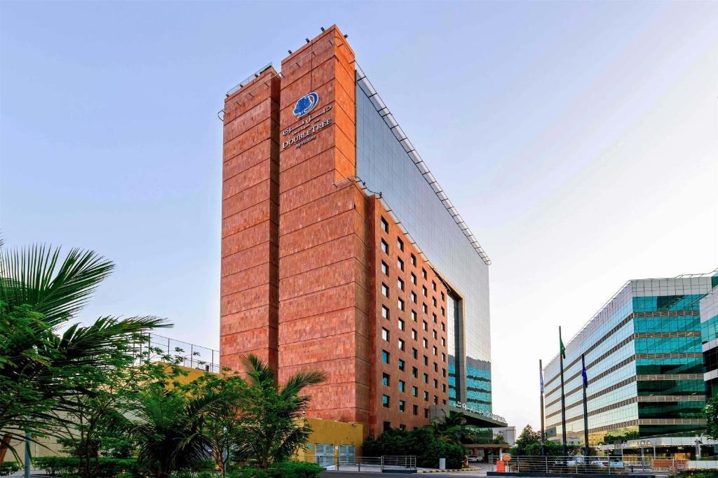 a tall red brick building with a clock on it at DoubleTree by Hilton Jeddah - Alandalus Mall in Jeddah