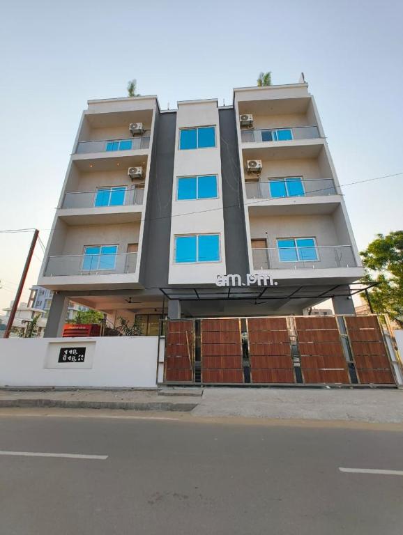 ein hohes Gebäude mit blauen Fenstern an einer Straße in der Unterkunft Hotel AM PM in Bhubaneshwar