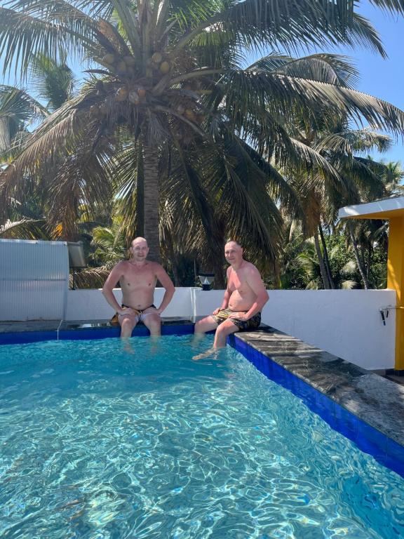 two men sitting on the edge of a swimming pool at Villa platinum 4 Bhk in Calangute