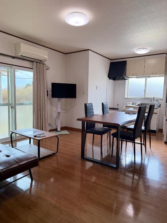 a living room with a dining room table and chairs at 宿Oshikiri 04 in Shibushi