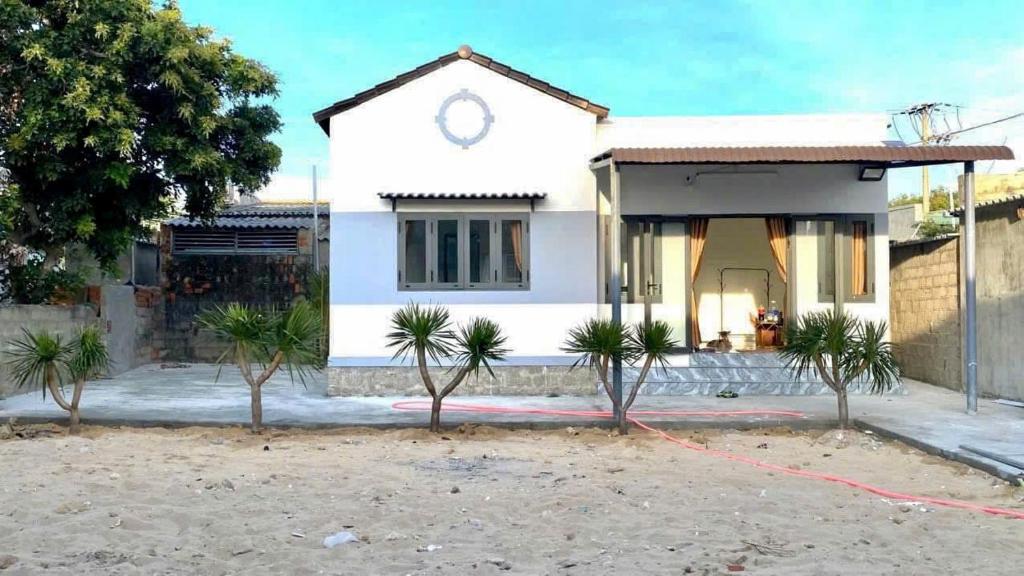 a white house with trees in front of it at Town Homestay in Thôn Sơn Hải