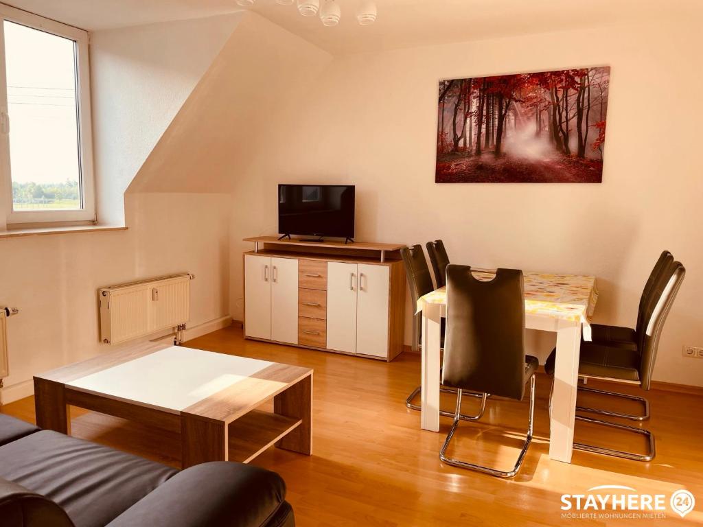 a living room with a table and a tv at StayHere24 Maisonette-Wohnung mit großem Garten in Leipzig