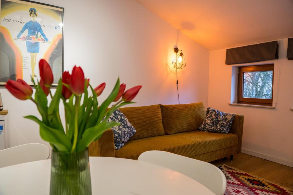 a living room with a couch and a table with red tulips at Apartamenty Centrum Biskupiec in Biskupiec