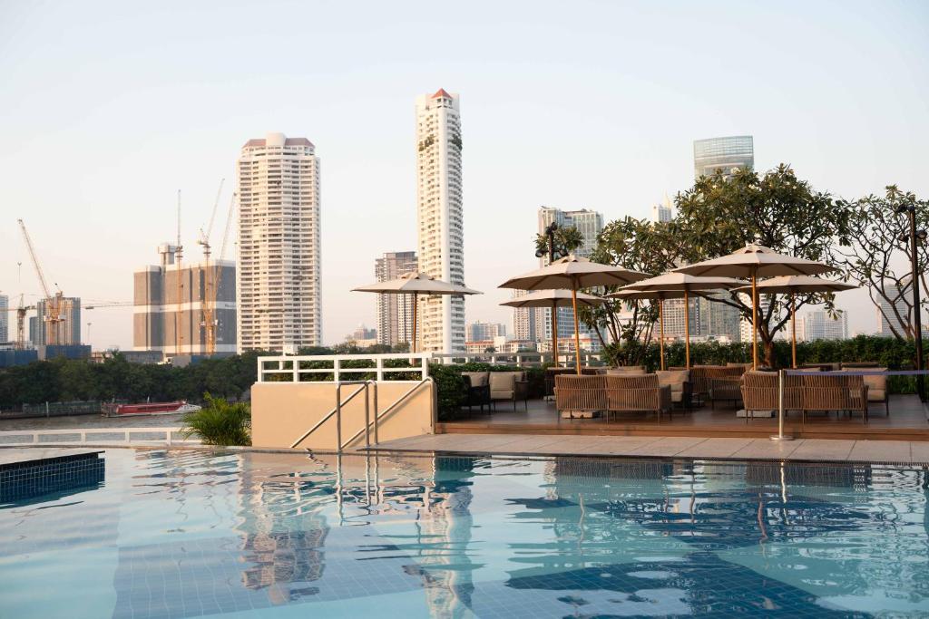 The outdoor pool looks toward Bangkok’s high-rises from a shaded deck.