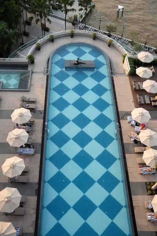 A long outdoor pool bordered by loungers and umbrella-shaded seating.