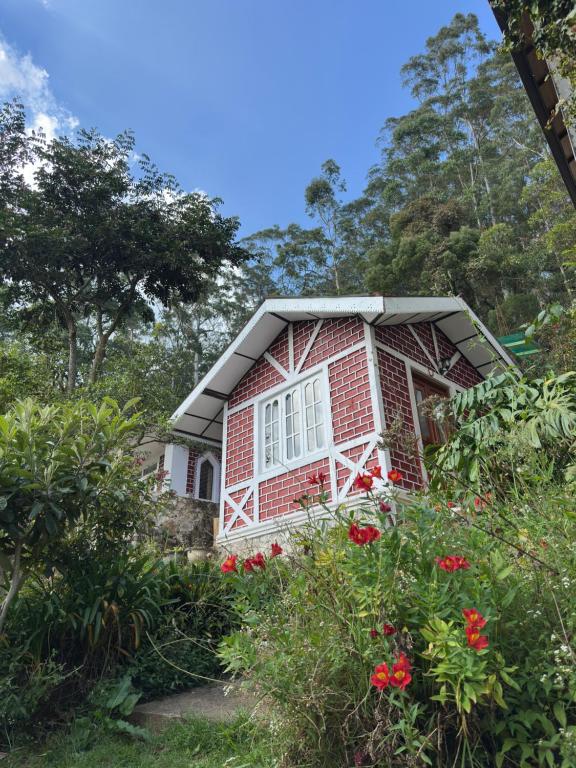 a red brick house with flowers in front of it at The Woodside Manor in Nuwara Eliya