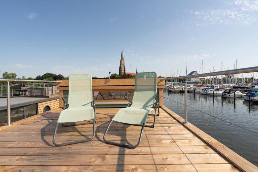 two chairs sitting on a dock next to the water at Hausboot Alma in Schleswig