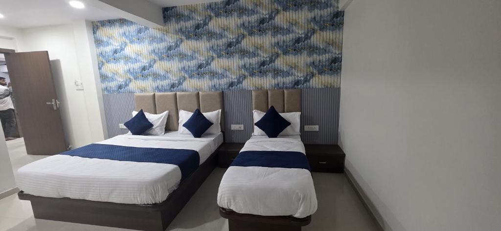 una camera da letto con due letti con cuscini blu e bianchi di Hotel New Rest Inn a Mahesāna