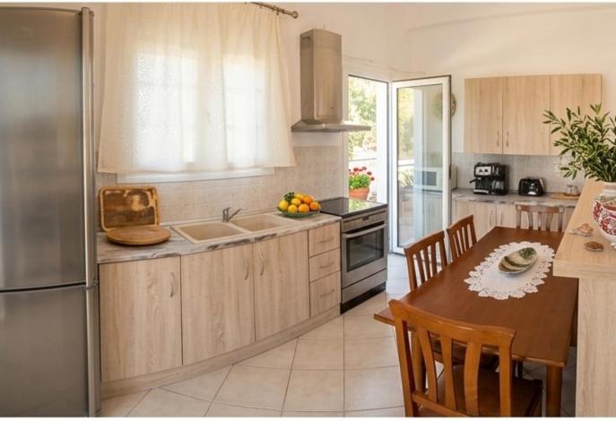 a kitchen with a table and a refrigerator and a table and chairs at Aegina House in Egina