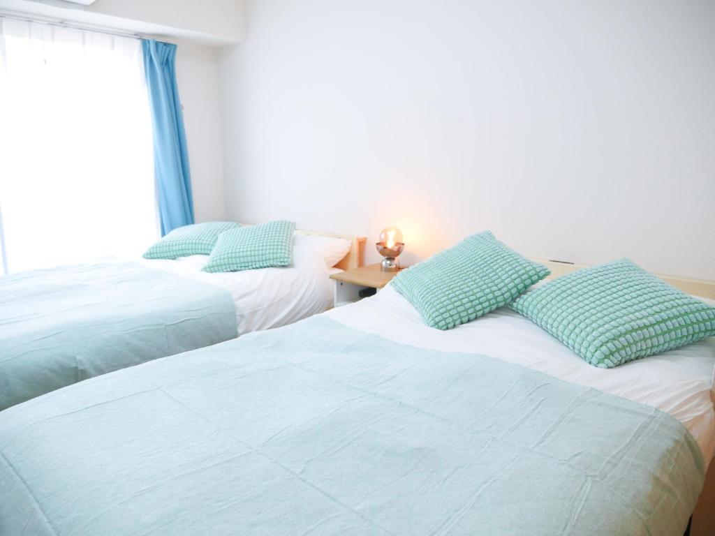 a bedroom with two beds with blue pillows on them at 9Stay川崎 in Kawasaki