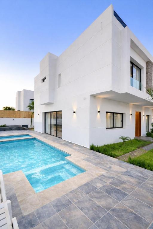 a white house with a swimming pool in front of it at Villa panorama Marrakech in Marrakesh