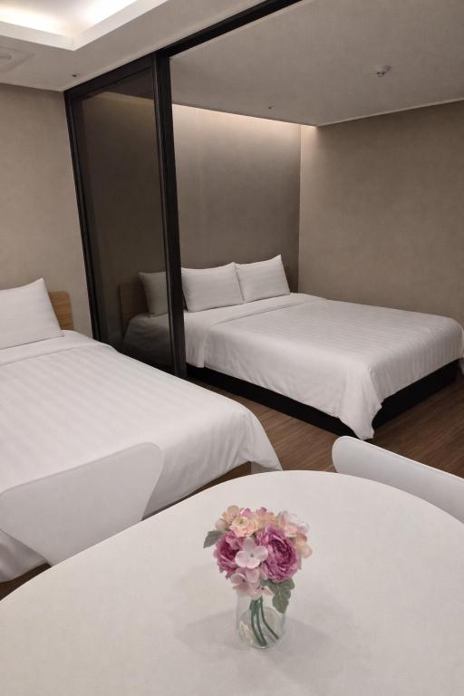 a room with two beds and a vase of flowers on a table at Haeon stay haeundae in Ch'ŏngsap'o