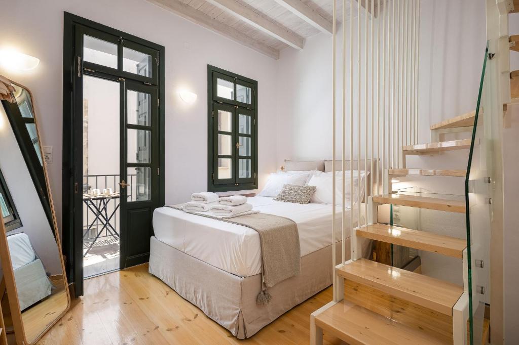 a white bedroom with a bed and a staircase at Old Town Stone Residence in Rethymno