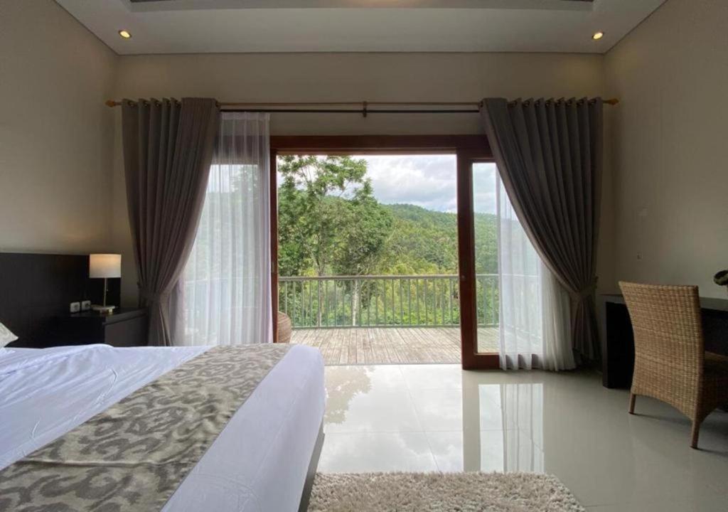 a bedroom with a bed and a sliding glass door at Nadira BnB in Munduk