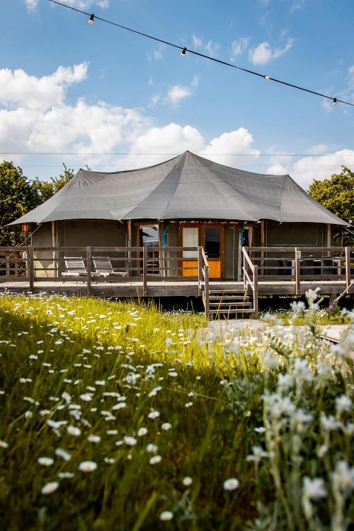 a large building with a tent in a field of flowers at Greenfields Glamping Durbuy in Durbuy
