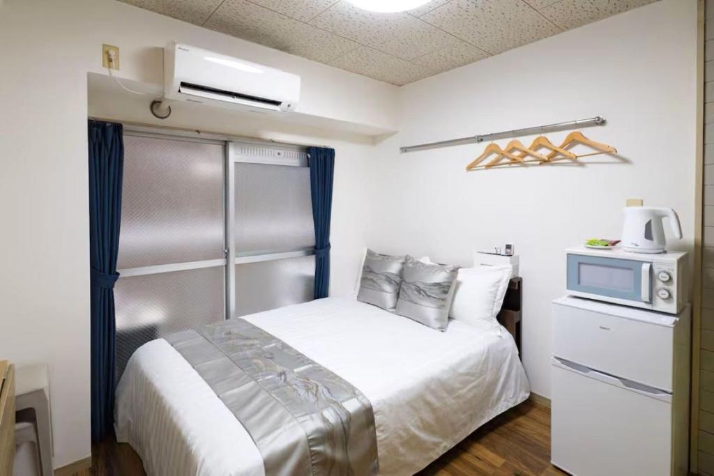 a bedroom with a bed with a microwave and a tv at コーポラス十日市 - supported by COCOSTAY in Hiroshima