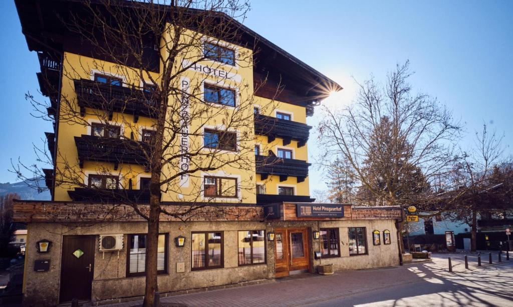a tall yellow building on the side of a street at Hotel Pinzgauerhof by Alpeffect Hotels in Zell am See