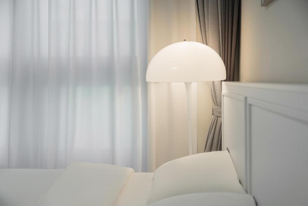 a living room with a white chair and a lamp at Daegu lily Residence Hotel in Daegu