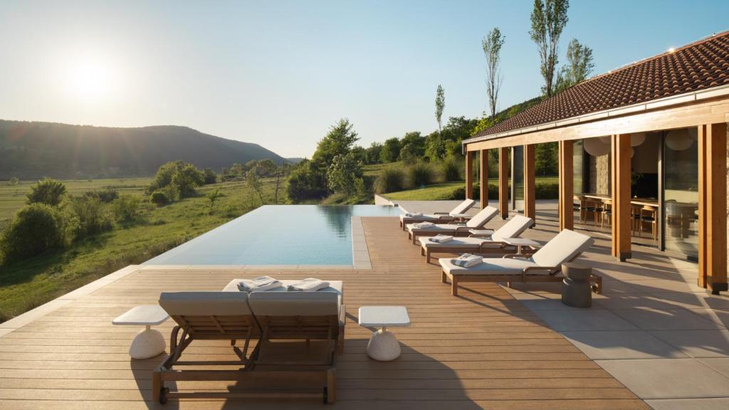 a row of lounge chairs on a deck with a pool at Villa Terra Moro - Split by Villas Guide in Crivac