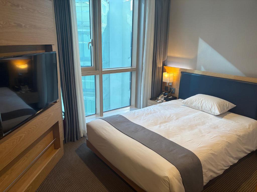 a hotel room with a bed and a large window at 센텀스위트호텔 in Busan