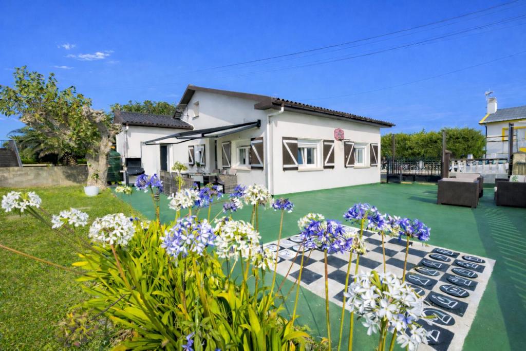 a house with a grass yard with flowers at Villa Las Catedrales - Piscina Privada - Frente a la playa - Amplio jardín in Barreiros