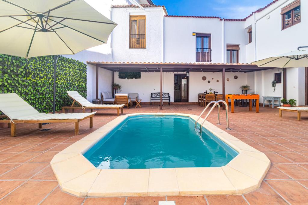 a house with a swimming pool and an umbrella at El Carmen - Villa Rural con Piscina Privada y Patio Andaluz in Ugíjar