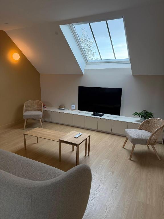 a living room with a flat screen tv and two chairs at Le Refuge des Clavendiers in Nuits-Saint-Georges