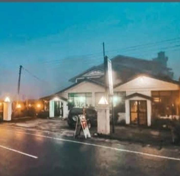 a building with a sign in a parking lot at night at Cool feel rest and cafe in Nuwara Eliya