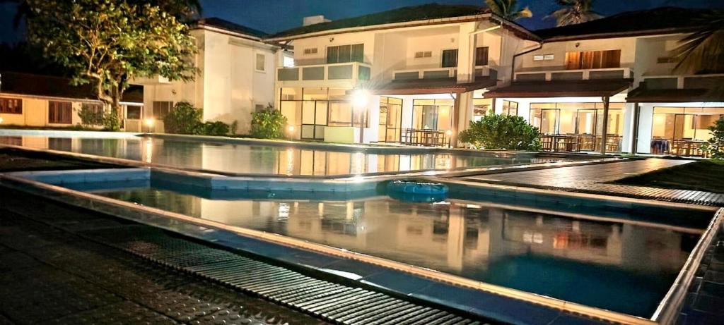 a swimming pool in front of a building at night at Sanmali Beach Hotel in Marawila
