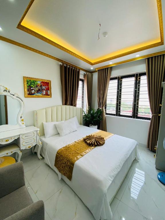 a bedroom with a large white bed and a desk at Hotel 24h in Hai Phong