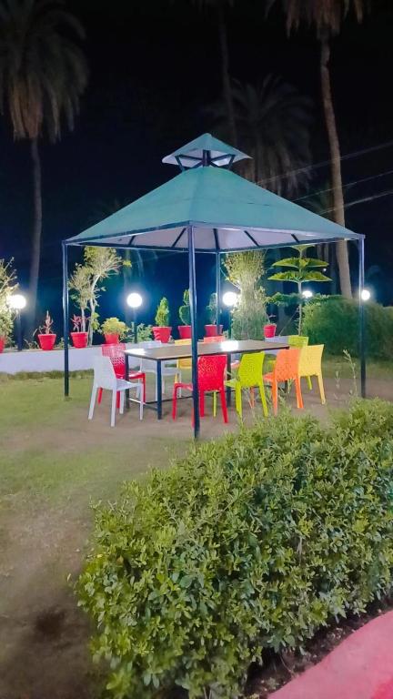 a table and chairs under an umbrella at night at Laxmanji villas in Mount Ābu