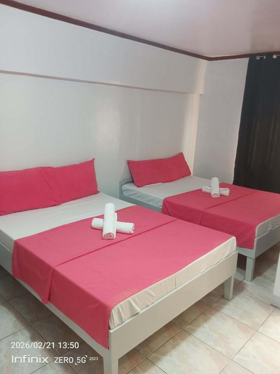two beds in a room with red and white sheets at Buena Lynnes Annex Lodge in Puerto Galera