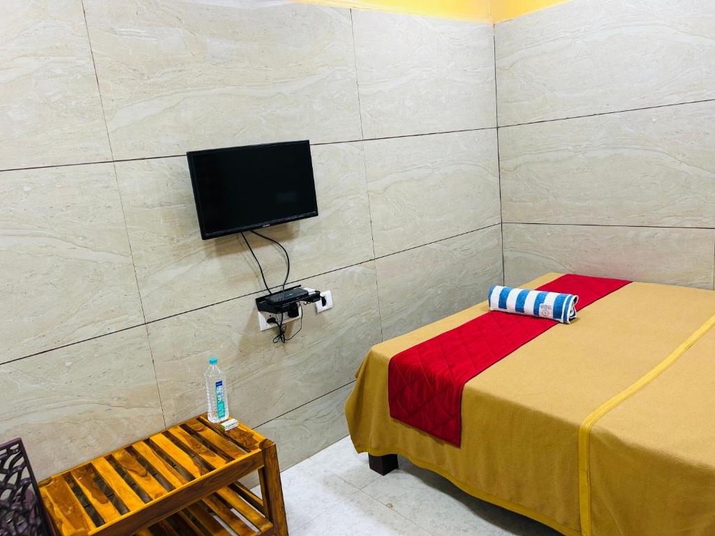 a room with two beds and a tv on a wall at GSR RESIDENCy in Kanchipuram