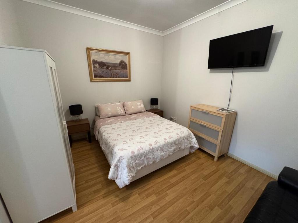 a bedroom with a bed and a flat screen tv at North Adelaide Studio in North Adelaide